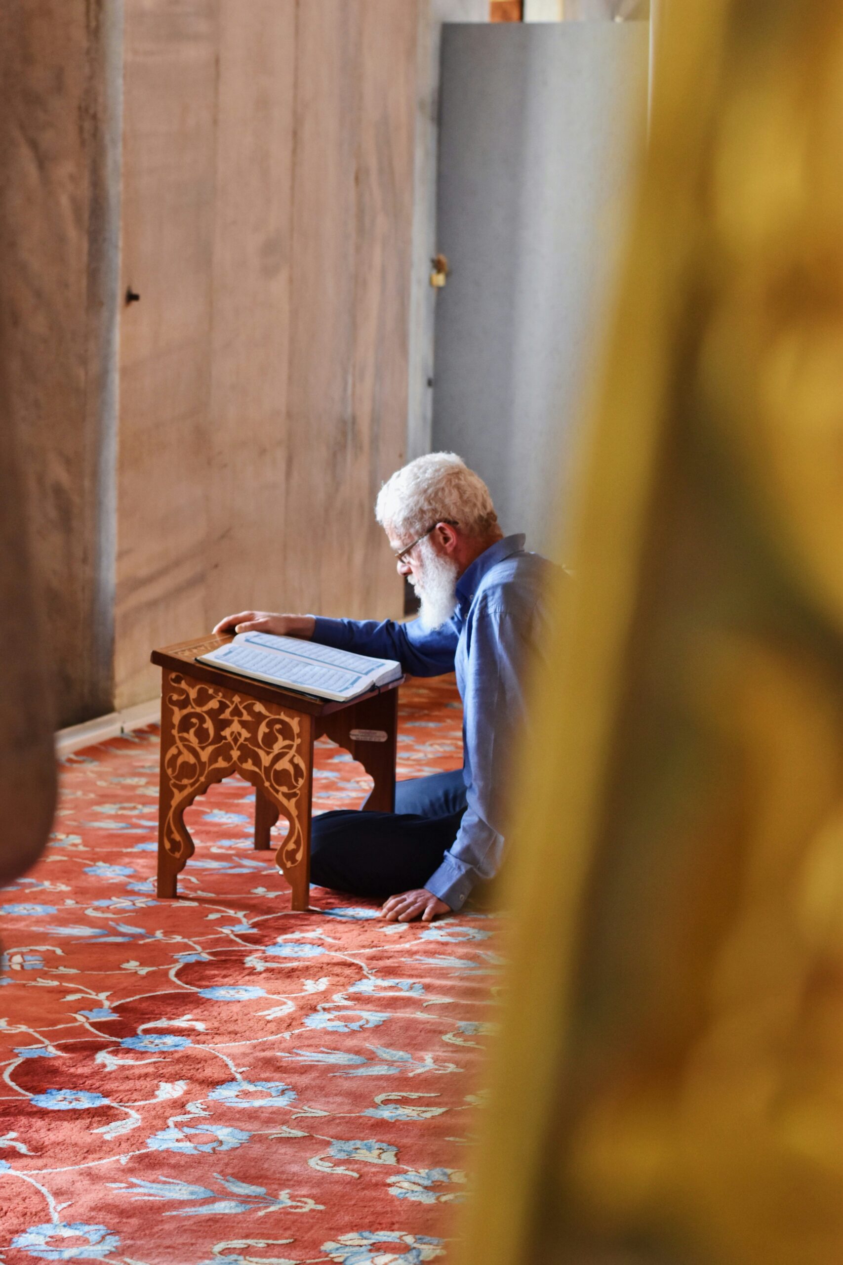 An old Muslim man reading the Quran in a mosque.