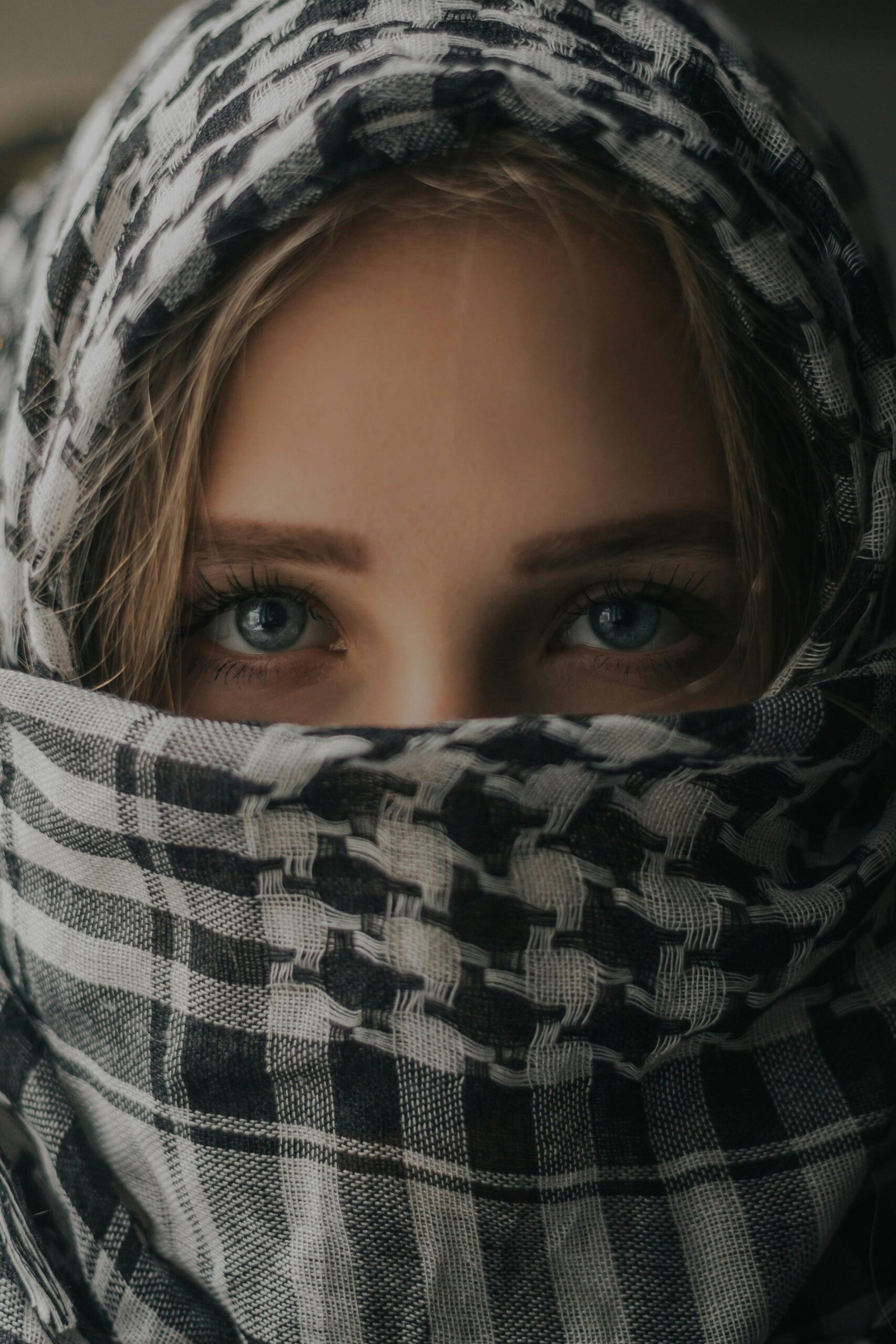 An young girl covering his face with a Palestinian scarf
