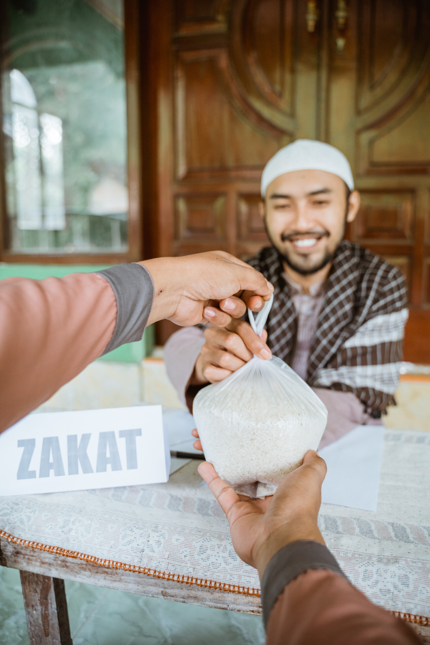 Muslim young man smiling while collecting charity from another man