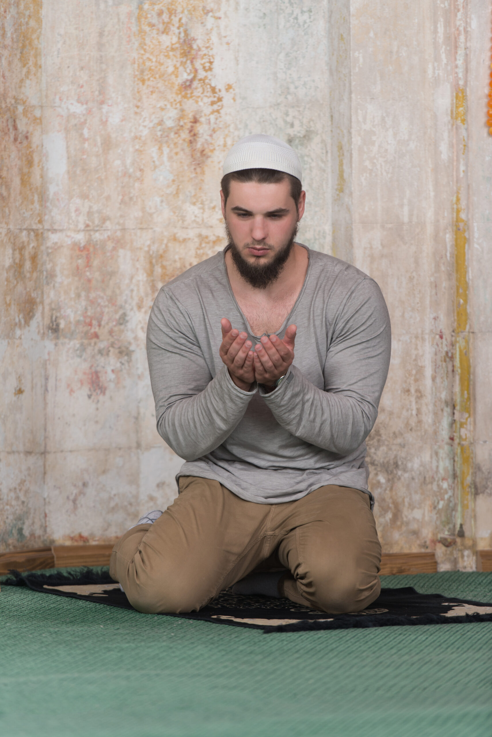 A young Muslim man praying in a mosque.