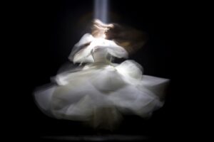 Ethereal figure spinning in light, blurred into ghostlike motion.