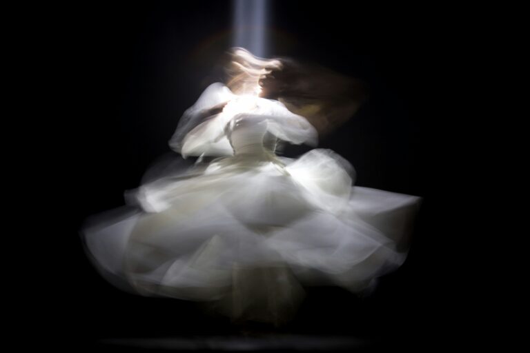 Ethereal figure spinning in light, blurred into ghostlike motion.