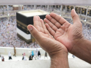 Two open hands reach upward in Mecca during pilgrimage , symbolizing hope and prayer.
