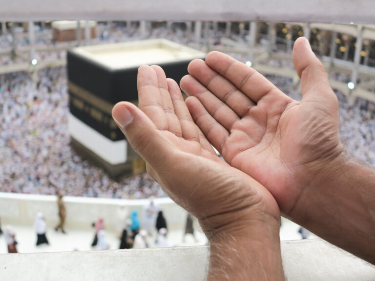 Two open hands reach upward in Mecca during pilgrimage , symbolizing hope and prayer.
