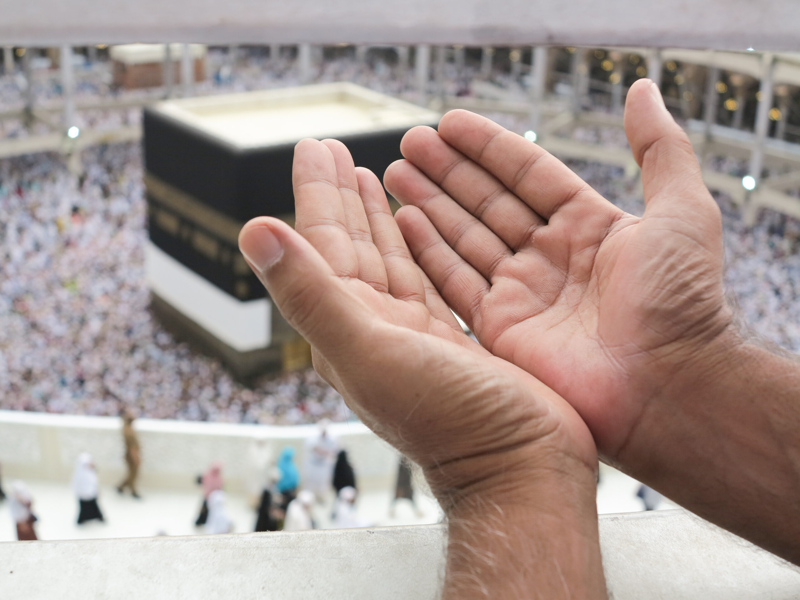 Two open hands reach upward in Mecca during pilgrimage , symbolizing hope and prayer.