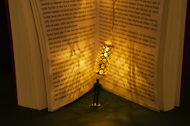 A figure near an open book with a hanging light fixture. The scene evokes knowledge and investigation.